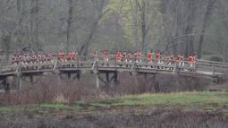 A column of British soldiers march over the wooden North Bridge in Concord.