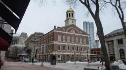 Brick three story building with a pediment creating a fourth story. Cupola with gilt dome sits atop.