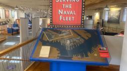 A diorama of a marine area sits under a banner reading "Serving the Naval Fleet"