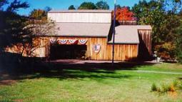 A green lawn leads to a low wooden building with a US flag flying in front