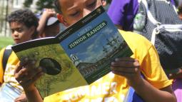 An African American child holding up the "Liberty Junior Ranger Activity Book."
