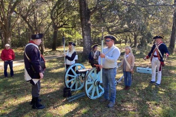 Image of tourists learning to fire a canon from costumed re-enactors